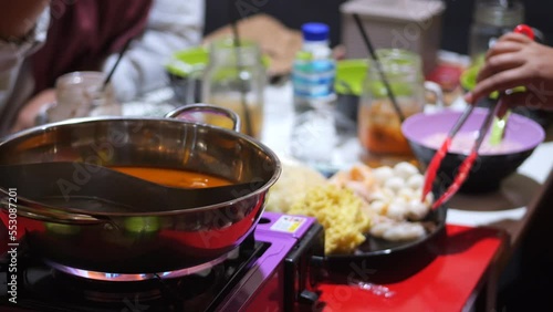  Selective focus korea steamboat pan on clove  at Tarakan, Indonesia. Group of Asian friends having party eating style local hot pot in indoor restaurant. photo