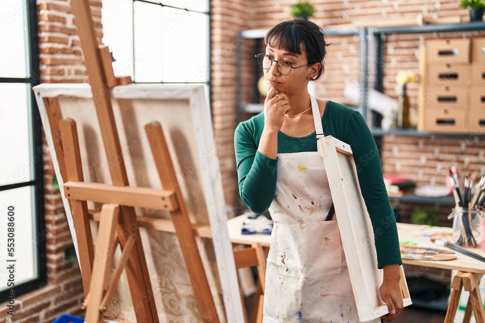 Young beautiful hispanic woman artist looking draw with doubt expression at art studio Young beautiful hispanic woman artist looking draw with doubt expression at art studio