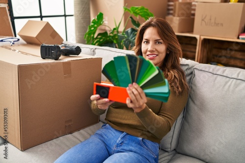 Young latin woman smiling confident choosing paint color at hew home