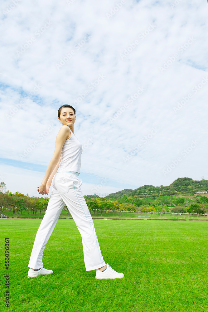 芝生のグラウンドでストレッチをする女性