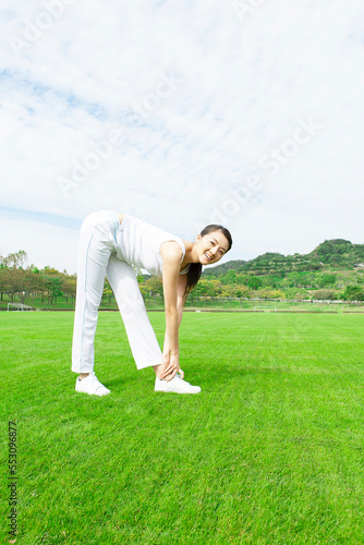 芝生のグラウンドでストレッチをする女性