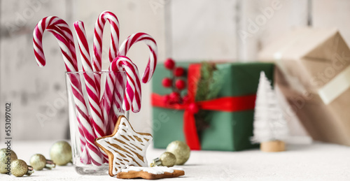Glass with candy canes, cookies and Christmas decor on table