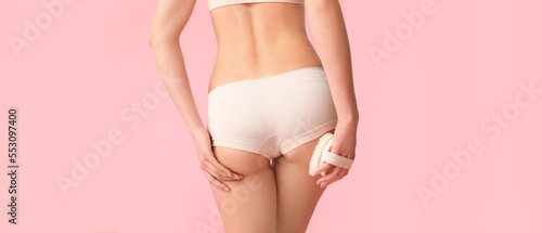 Woman with anti-cellulite massage brush on pink background