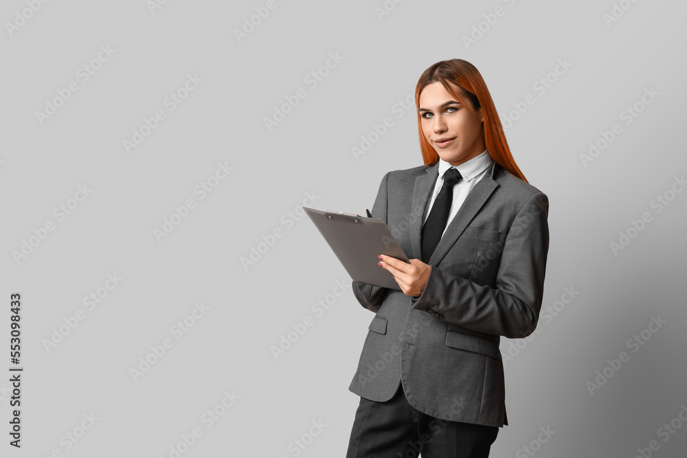 Beautiful transgender secretary with clipboard on grey background Beautiful transgender secretary with clipboard on grey background
