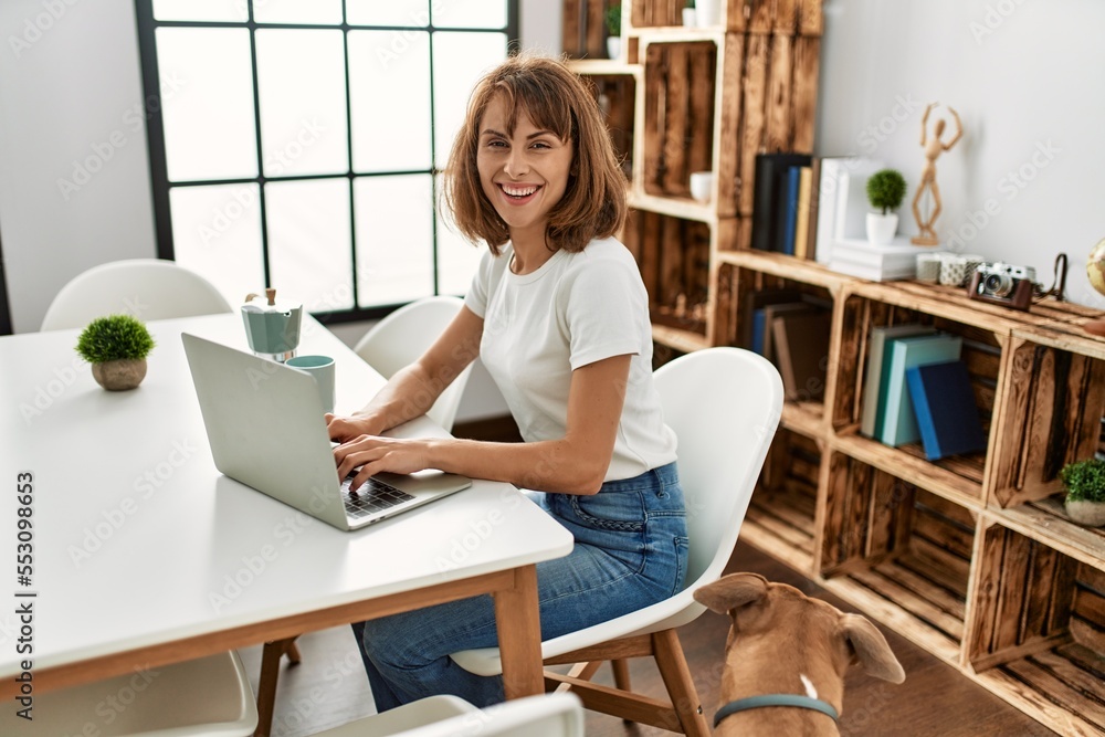 Young caucasian woman using laptop sitting on table at home Young caucasian woman using laptop sitting on table at home