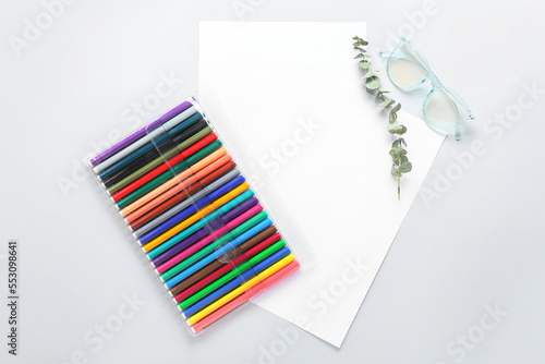 Blank paper sheets with felt-tip pens, eucalyptus branch and eyeglasses on light background