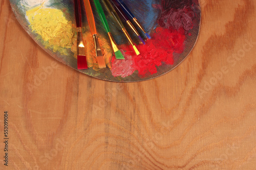 Art palette, brushes, paints, tulips on a wooden texture background. Copy space. Place for text.