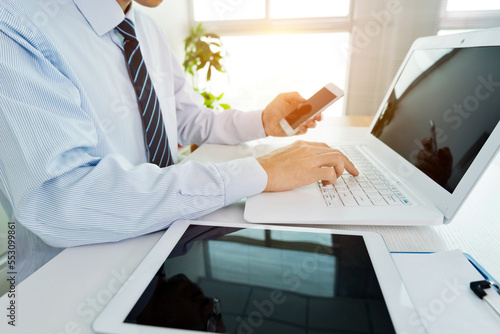 Businessman in office using laptop, tablet and smart phone on the desk