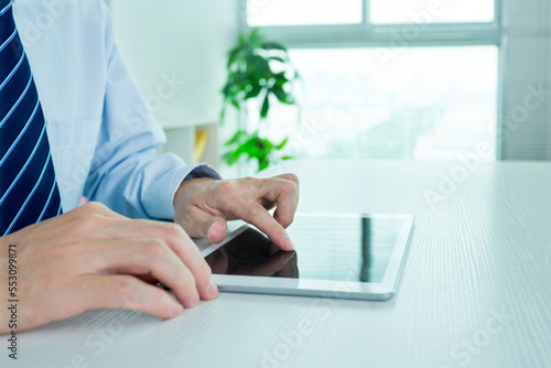 Close up of businessman working on his digital tablet