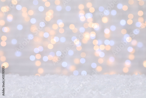 Snow against blurred Christmas lights