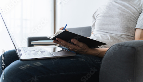 University student using laptop or computer for studying or learning book, reading textbook at home. Knowledge and skill training online at home. Education and cognition success idea concept