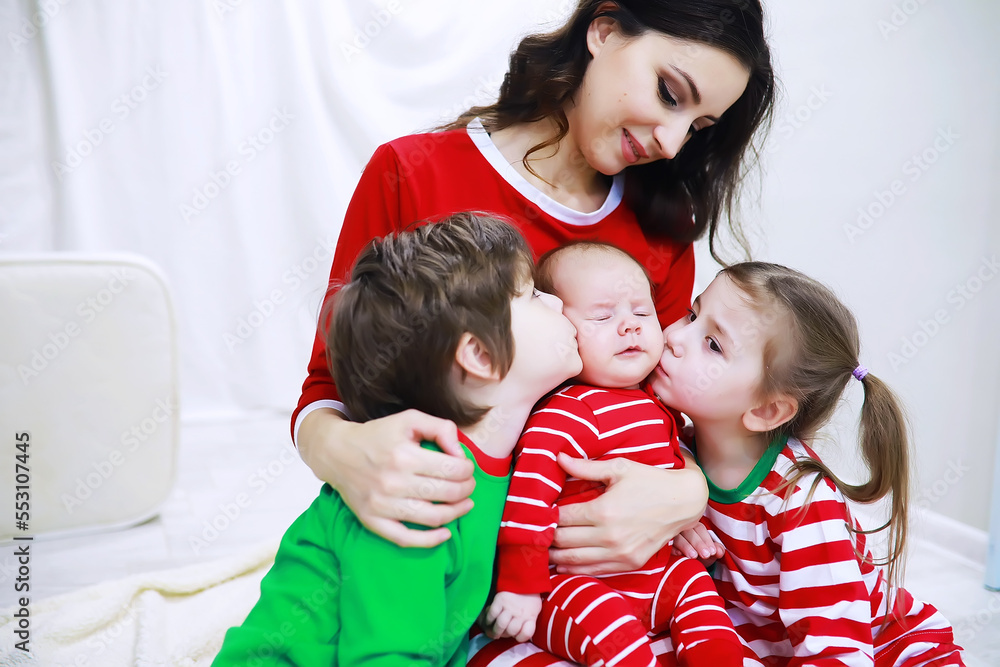 A family in striped pajamas is resting at home. Little children dressed as elves are lying on the sofa. Happy family.
