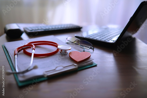 Doctor`s desk in the clinic's office. Stethoscope, test tubes, laptop, prescriptions on the table.