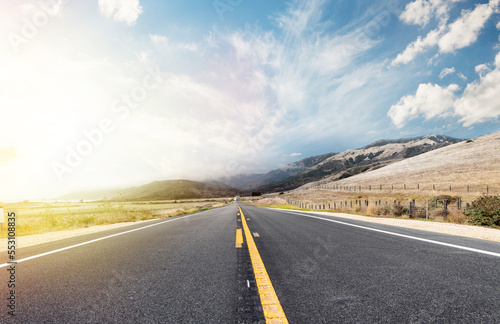 Asphalt road and country landscape with sunny sky