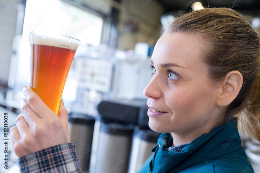 female worker examining glass of beer female worker examining glass of beer