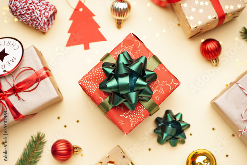Gift box with bow and Christmas balls on beige background, closeup