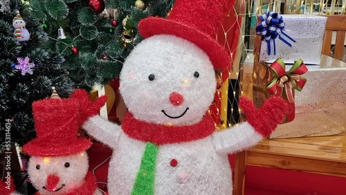 Christmas tree ornaments, sparkling snowman on christmas tree lights on holiday background.