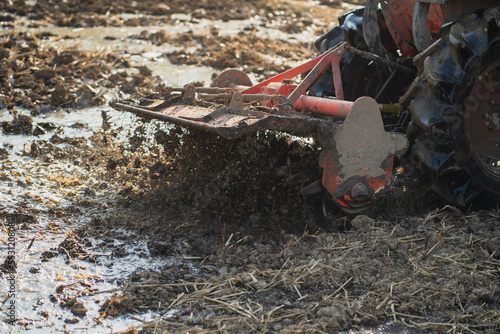 Agricultural tractors are plowing the soil in preparation for planting.