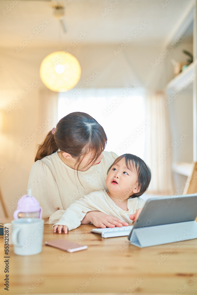 赤ちゃんを抱えてパソコンを操作する女性 赤ちゃんを抱えてパソコンを操作する女性