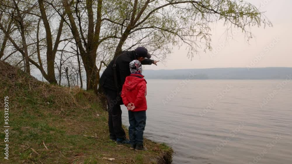 Father and son on the lake. A man is showing something to a boy of 5-6 years old. Family walks Father and son on the lake. A man is showing something to a boy of 5-6 years old. Family walks