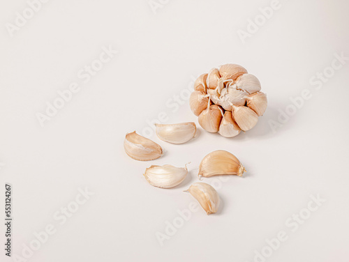 Large head of garlic and small cloves arranged on white background Put yourself aside to have copy space.