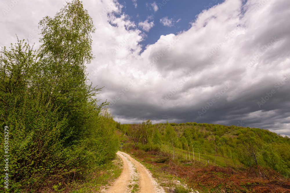 Beautiful country road in spring in remote rural area in Eastern Europe and storm April sky Beautiful country road in spring in remote rural area in Eastern Europe and storm April sky