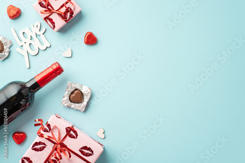 Valentine's Day concept. Top view photo of gift boxes heart shaped chocolate candies wine bottle and inscription love you on isolated pastel blue background with copyspace