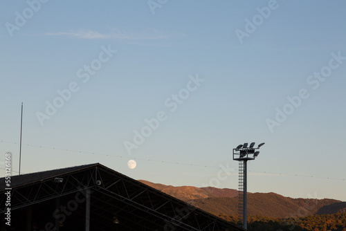 landscape at sunset with sports facilities and full moon in the background in clear sky