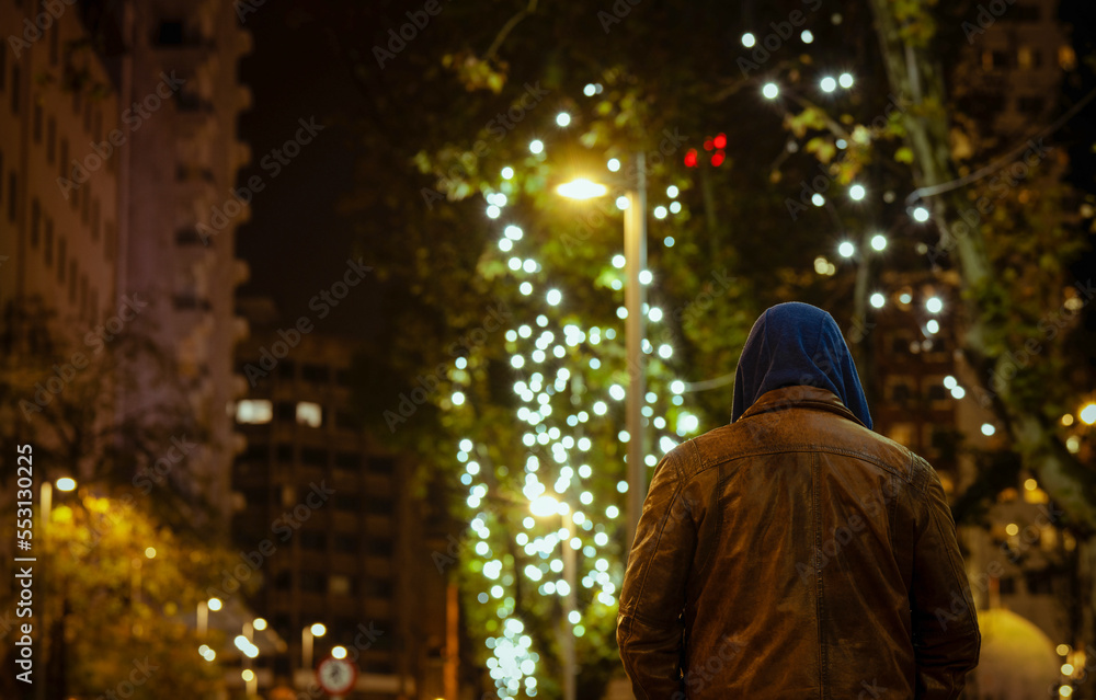 Rear view of adult man on street at night with lights of Christmas Rear view of adult man on street at night with lights of Christmas
