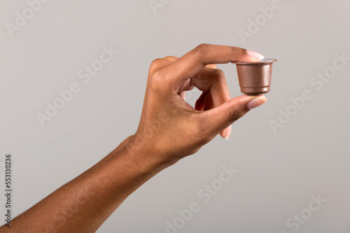 Black female hand showing coffee capsule photo