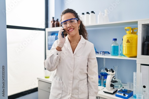 Young beautiful hispanic woman scientist talking on smartphone at laboratory