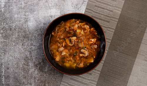 Shchi - traditional russian cabbage soup with beef, mushrooms, sauerkraut in a bowl on a dark background. Top view, flat lay