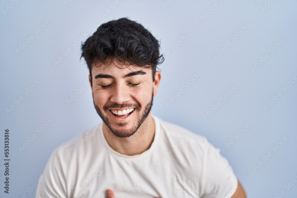 Hispanic man with beard standing over white background smiling and laughing hard out loud because funny crazy joke with hands on body. Hispanic man with beard standing over white background smiling and laughing hard out loud because funny crazy joke with hands on body.