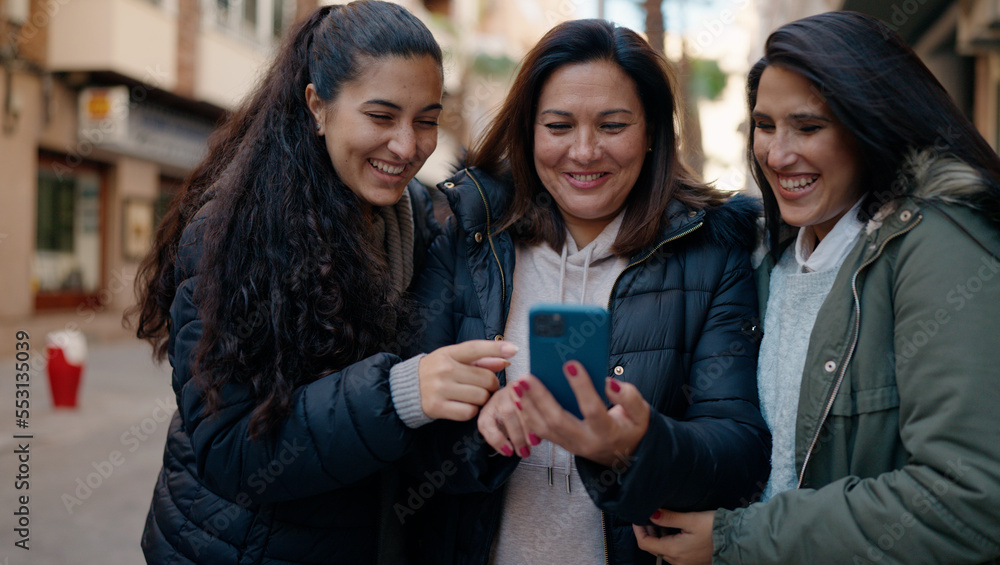 Mother and daugthers using smartphone standing together at street Mother and daugthers using smartphone standing together at street