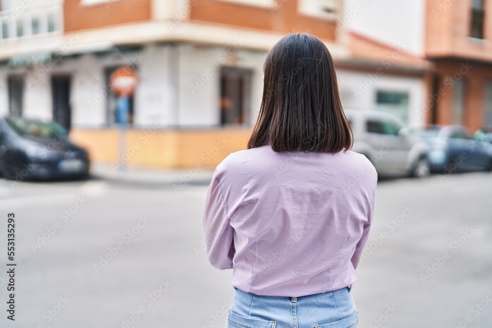 Young hispanic woman standing on back view at street