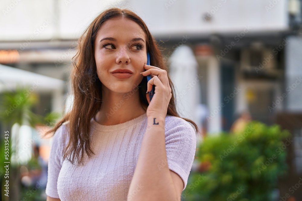 Young woman smiling confident talking on the smartphone at street
