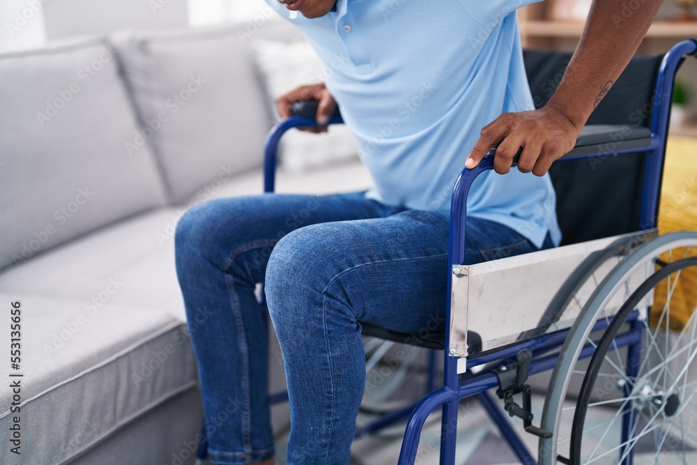 Obraz premium Young latin man sitting on wheelchair at home