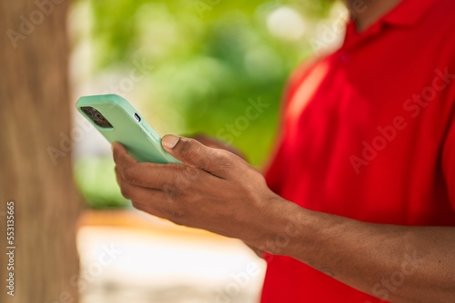 Young latin man using smartphone at park