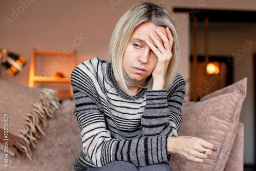 Tired upset woman worried about tiredness from domestic work sitting at couch