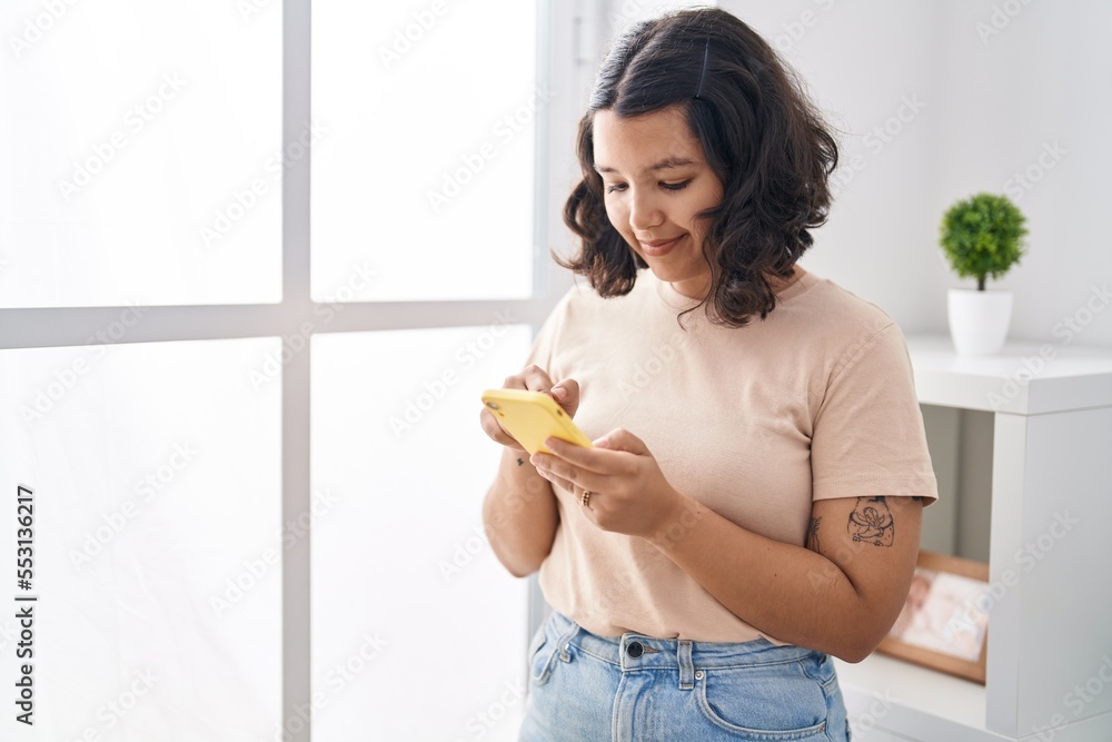 Young woman using smartphone standing at home Young woman using smartphone standing at home