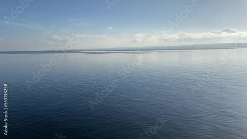 Crystal clear air over the lake of Constance. Beautiful, dark blue, and calm water of a lake. Deep blue water pan shot. Drone-like shot flying over a lake. Beautiful lens flares and reflections. 