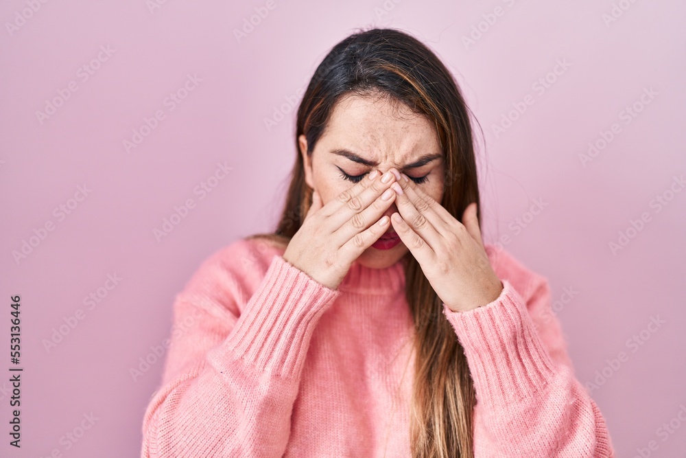 Young hispanic woman standing over pink background rubbing eyes for fatigue and headache, sleepy and tired expression. vision problem Young hispanic woman standing over pink background rubbing eyes for fatigue and headache, sleepy and tired expression. vision problem