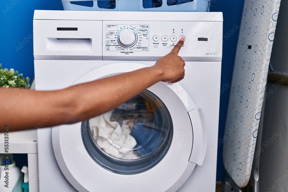 African american woman turning on washing machine at laundry room African american woman turning on washing machine at laundry room