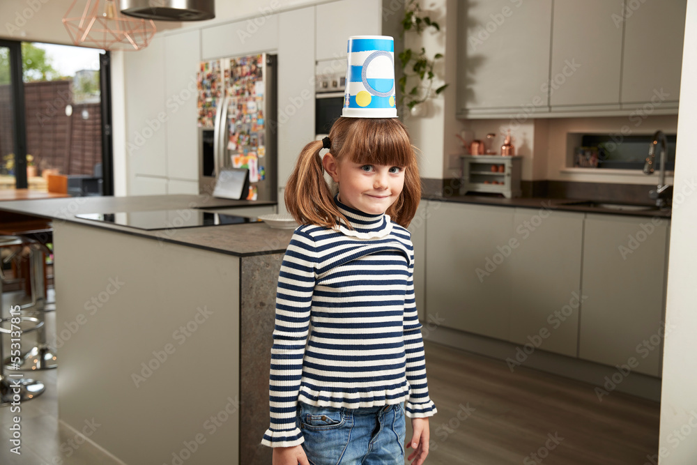 Smiling girl standing with plastic container on head at home Smiling girl standing with plastic container on head at home
