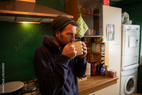 Man drinking coffee in kitchen at home photo