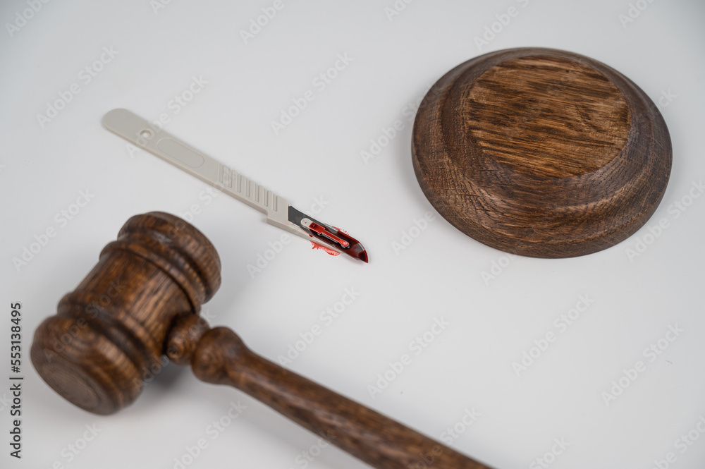 A scalpel covered in blood and a judge's wooden gavel.
