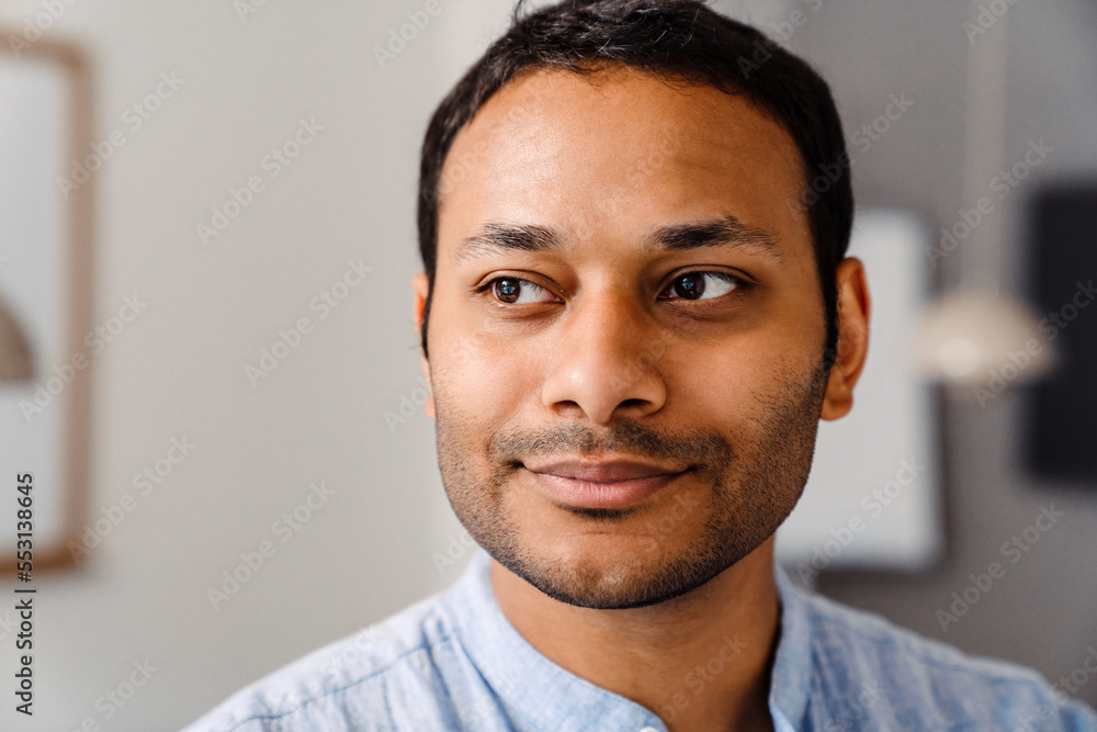 Close up of young indian man standing in office Close up of young indian man standing in office
