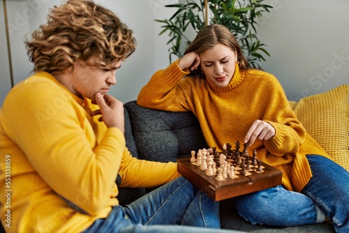Young caucasian couple concentrate playing chess at home