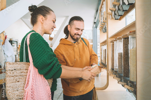 Smiling couple discussing over food package in zero waste store photo