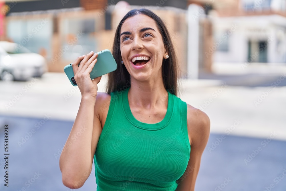 Young beautiful hispanic woman miling confident listening audio message by the smartphone at street
